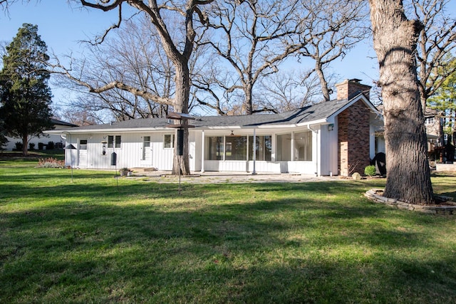 rear view of house featuring a sunroom and a lawn