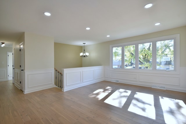 unfurnished room featuring light hardwood / wood-style floors and a notable chandelier