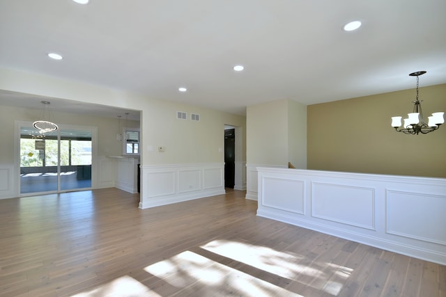 unfurnished room with light hardwood / wood-style flooring and a notable chandelier