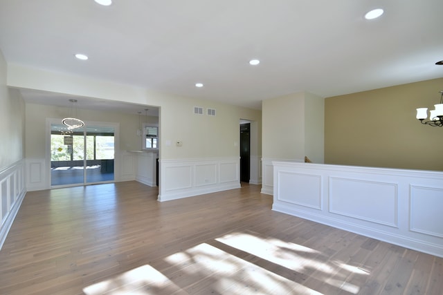 spare room featuring a chandelier and light wood-type flooring