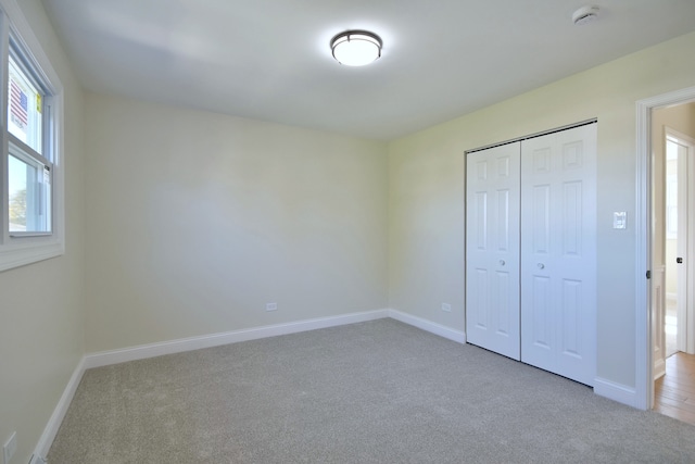 unfurnished bedroom with a closet and light colored carpet