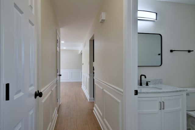 hall with light hardwood / wood-style floors and sink