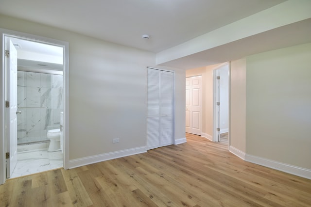 unfurnished bedroom featuring light wood-type flooring and ensuite bath