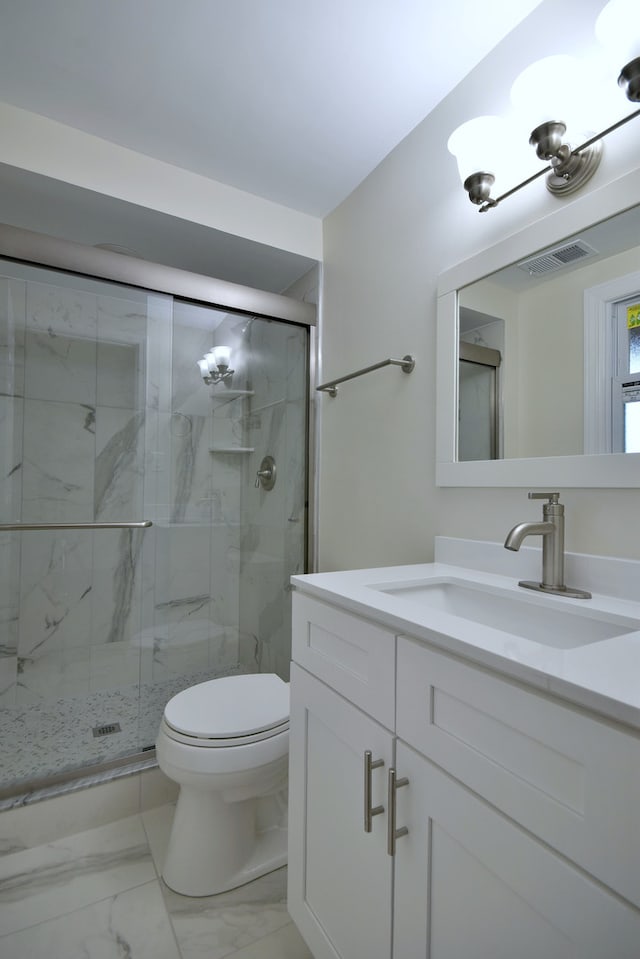 bathroom featuring a shower with door, vanity, and toilet