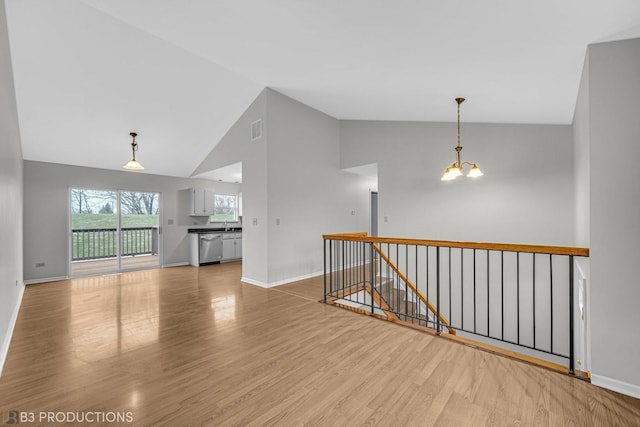 spare room featuring a notable chandelier, light hardwood / wood-style floors, and high vaulted ceiling