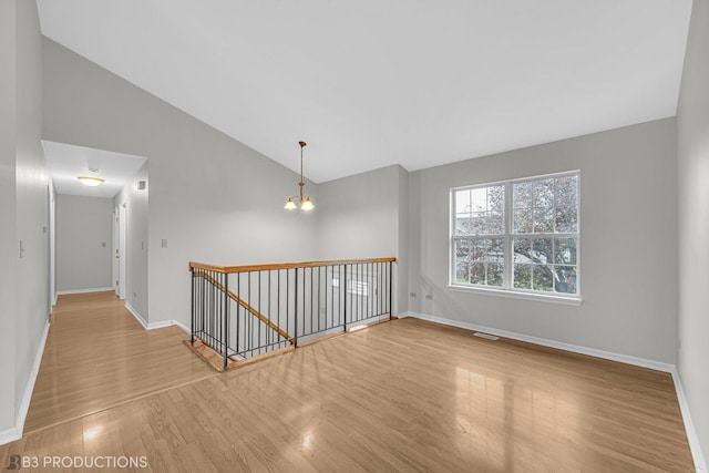 unfurnished room featuring a chandelier, high vaulted ceiling, and light hardwood / wood-style flooring