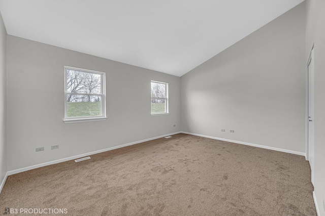 carpeted spare room with vaulted ceiling