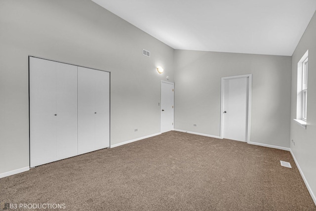 unfurnished bedroom featuring carpet floors, high vaulted ceiling, and a closet