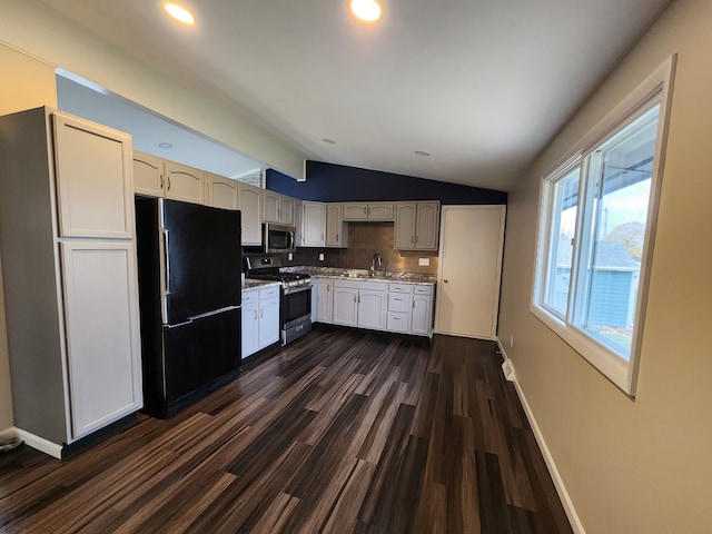 kitchen featuring appliances with stainless steel finishes, dark hardwood / wood-style flooring, backsplash, sink, and lofted ceiling