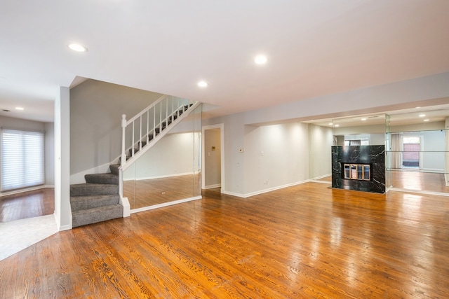 unfurnished living room featuring a premium fireplace and wood-type flooring