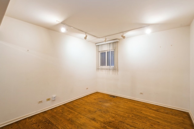 empty room with rail lighting and dark hardwood / wood-style floors