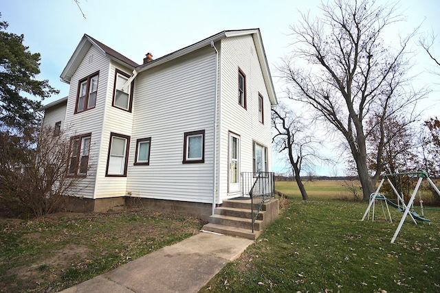 view of home's exterior with a playground and a lawn