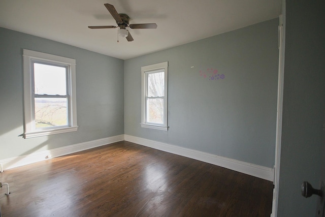 empty room with ceiling fan, a healthy amount of sunlight, and dark hardwood / wood-style floors