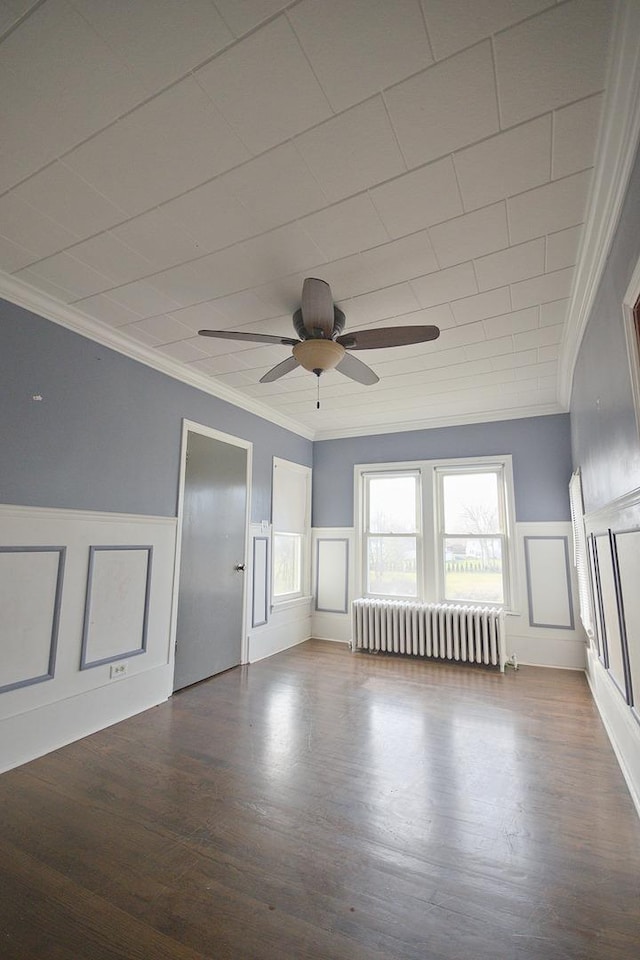 empty room with hardwood / wood-style flooring, ceiling fan, radiator heating unit, and ornamental molding