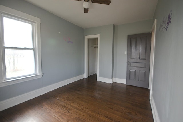 unfurnished bedroom featuring dark hardwood / wood-style flooring, a closet, multiple windows, and ceiling fan