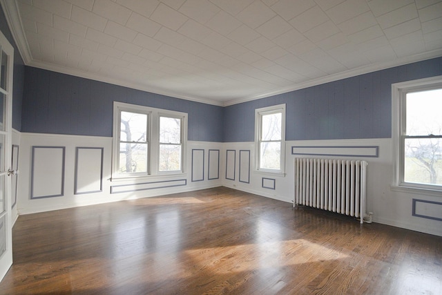 spare room with radiator heating unit, dark hardwood / wood-style floors, plenty of natural light, and ornamental molding