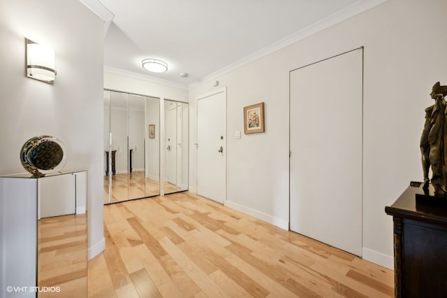 corridor with light hardwood / wood-style floors and ornamental molding