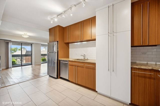 kitchen with appliances with stainless steel finishes, backsplash, light stone counters, and sink