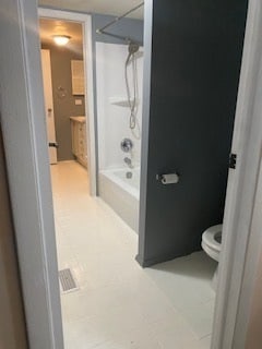 bathroom featuring tile patterned flooring, toilet, and tub / shower combination