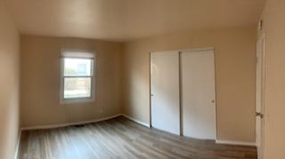 unfurnished bedroom with wood-type flooring and a closet