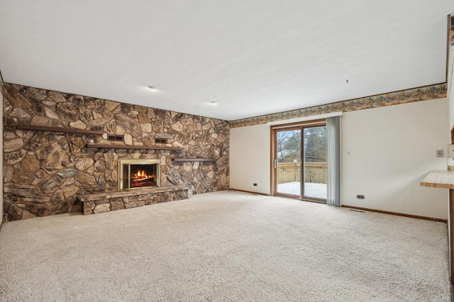 unfurnished living room with carpet flooring and a stone fireplace