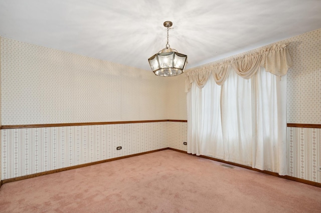 carpeted spare room featuring a notable chandelier