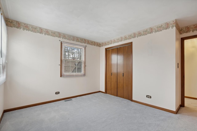 unfurnished bedroom featuring light carpet and a closet