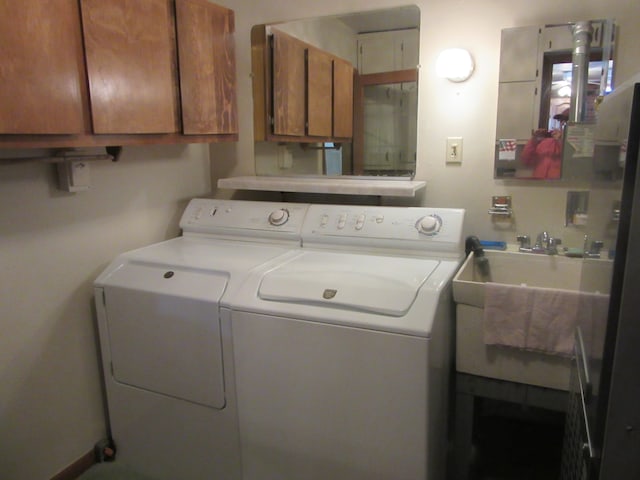 clothes washing area featuring cabinets, sink, and washing machine and clothes dryer