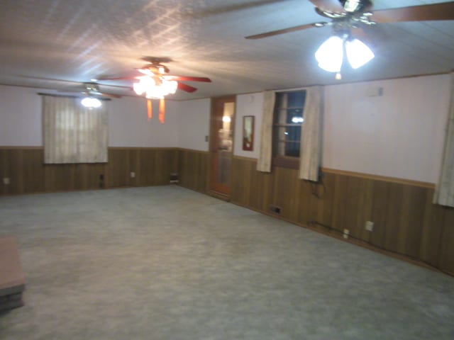 carpeted empty room featuring ceiling fan and wooden walls