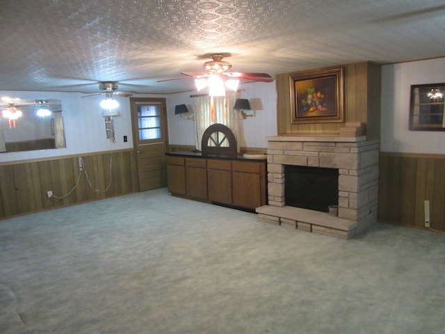 living room featuring a fireplace, a textured ceiling, light colored carpet, and wood walls