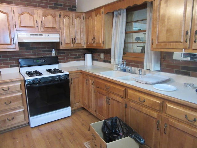 kitchen featuring backsplash, sink, light hardwood / wood-style floors, and white gas range oven