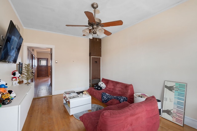 living room with crown molding, ceiling fan, and light wood-type flooring