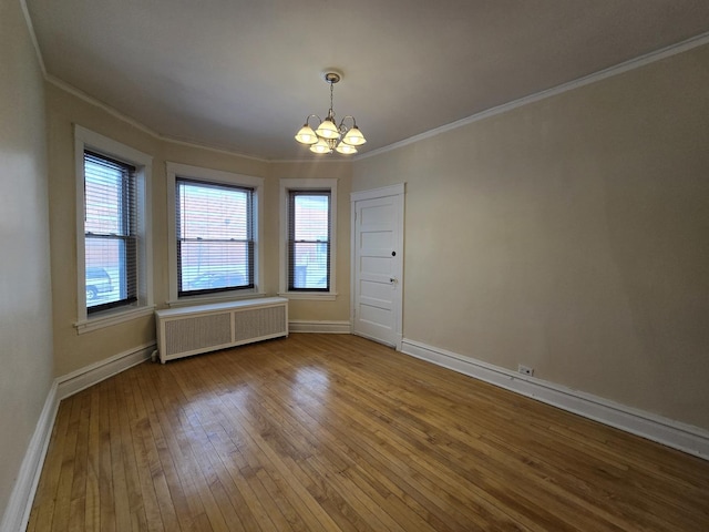 unfurnished room with an inviting chandelier, radiator, crown molding, and hardwood / wood-style floors