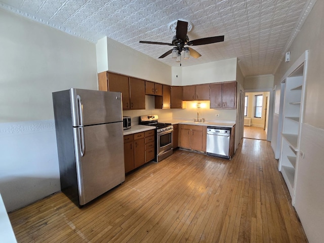 kitchen featuring appliances with stainless steel finishes, sink, ceiling fan, and light hardwood / wood-style flooring