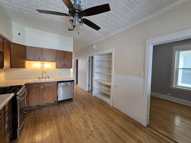 kitchen with sink, stainless steel appliances, a textured ceiling, built in shelves, and light wood-type flooring