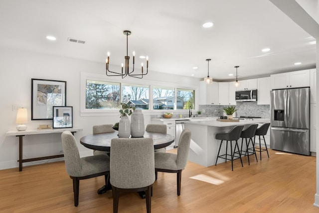 dining room featuring light wood-type flooring, a wealth of natural light, and a notable chandelier