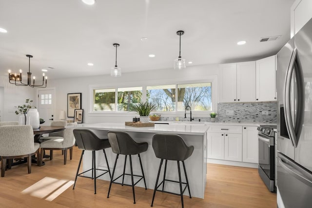 kitchen with a wealth of natural light, light hardwood / wood-style floors, white cabinetry, and appliances with stainless steel finishes