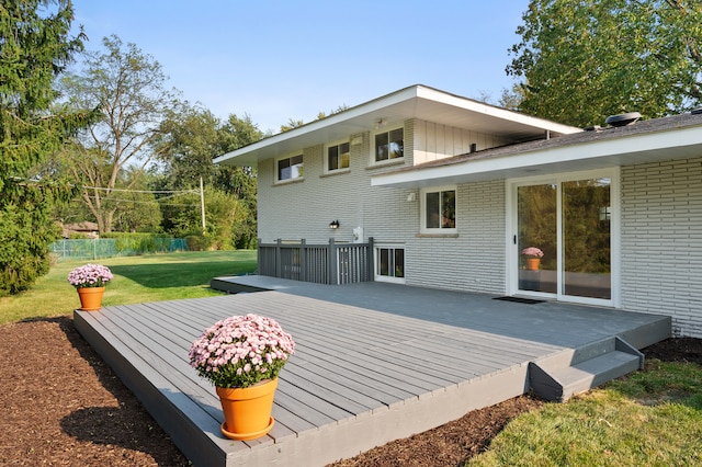 rear view of house featuring a lawn and a wooden deck