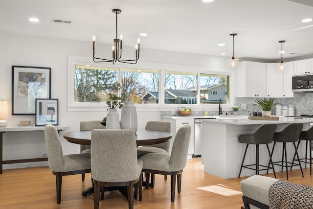 dining room with light wood-type flooring, an inviting chandelier, and sink