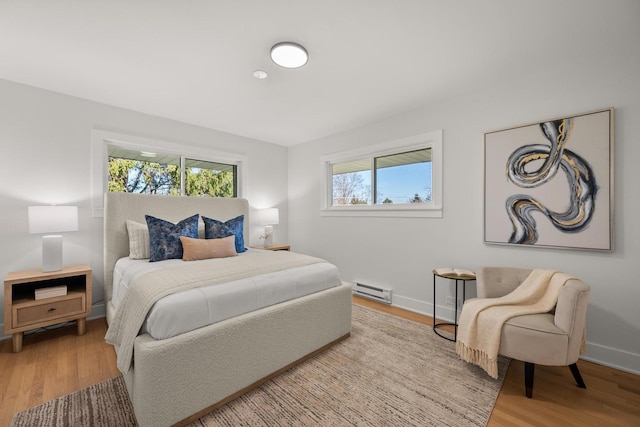 bedroom featuring light hardwood / wood-style floors and a baseboard heating unit