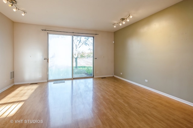 spare room with track lighting and light wood-type flooring