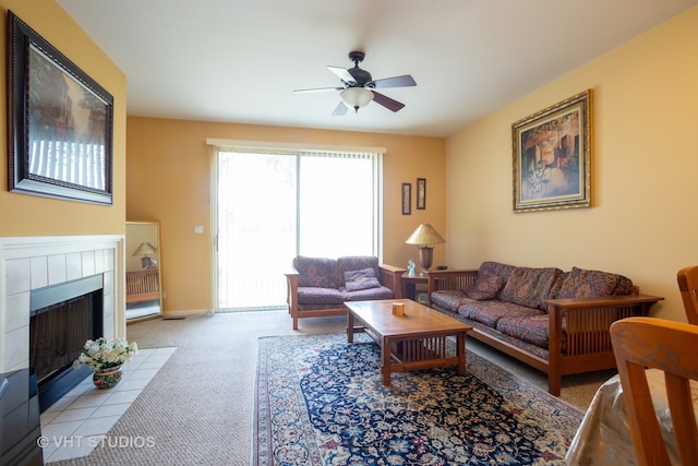 living room featuring a tile fireplace, light carpet, and ceiling fan