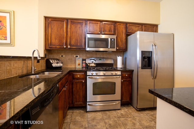 kitchen featuring sink, dark stone countertops, decorative backsplash, light tile patterned flooring, and appliances with stainless steel finishes