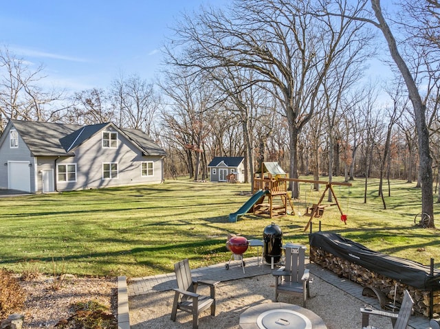 view of yard featuring a patio, a playground, and an outdoor fire pit