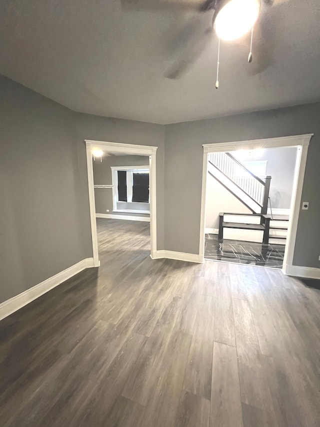 unfurnished living room featuring ceiling fan and dark wood-type flooring