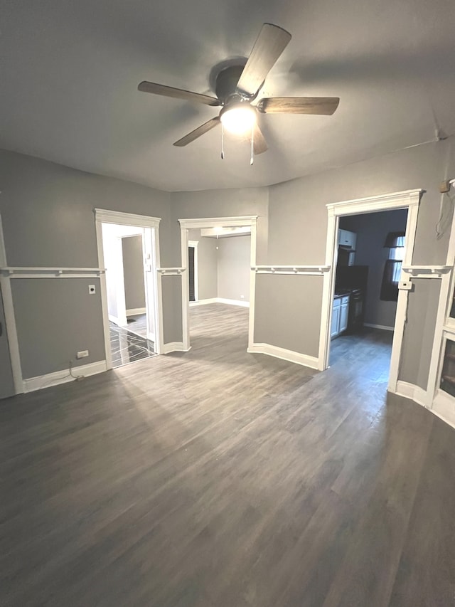 unfurnished living room with dark hardwood / wood-style flooring and ceiling fan