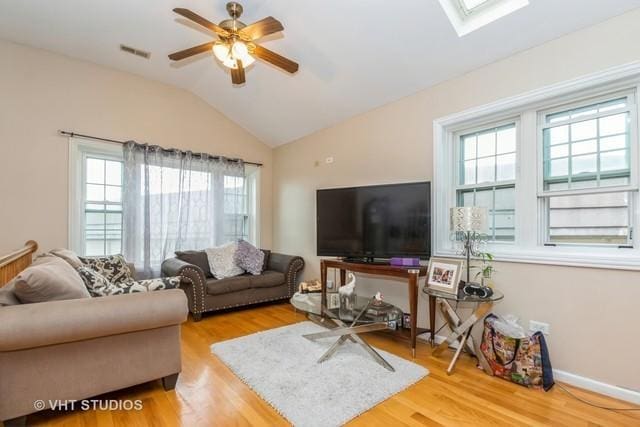 living room featuring hardwood / wood-style flooring, plenty of natural light, ceiling fan, and lofted ceiling with skylight