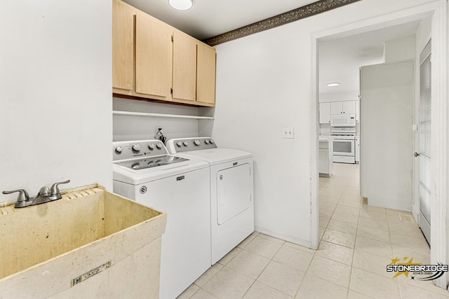 washroom featuring cabinets, sink, light tile patterned floors, and washer and clothes dryer