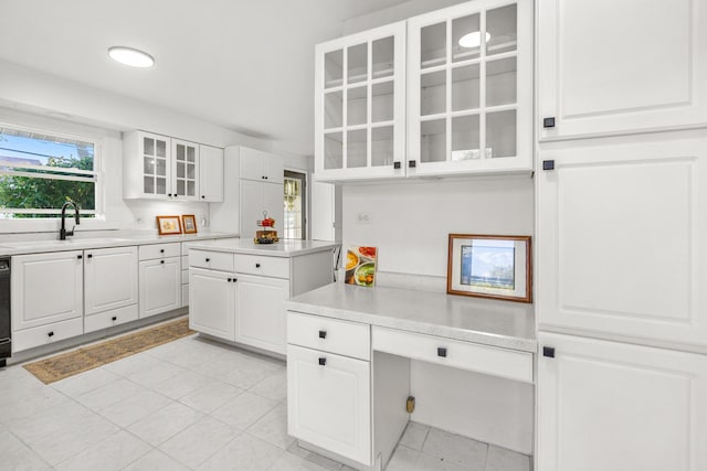 kitchen featuring light tile patterned floors, built in desk, sink, and white cabinets