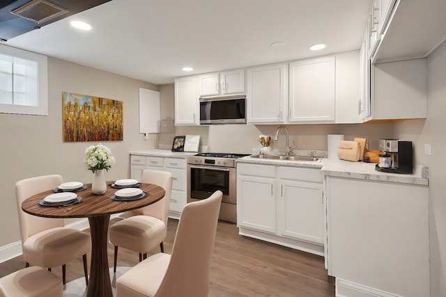 kitchen featuring white cabinetry, sink, light hardwood / wood-style floors, and appliances with stainless steel finishes